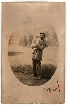 PRAHA (PRAGUE), THE CZECHOSLOVAK REPUBLIC - APRIL 29, 1928: Vintage photo shows man cradles a small baby. Retro black and white photography. Circa 1930s.