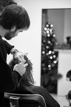 Beautiful young woman in modern hair salon. hairdresser checking hairstyle of caucasian girl