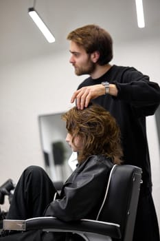 Beautiful young woman in modern hair salon. hairdresser checking hairstyle of caucasian girl