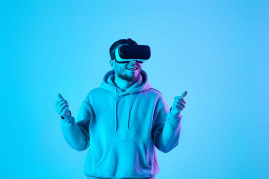 young man vr glasses playing video games on blue background. Neon lighting. online game and entertainment