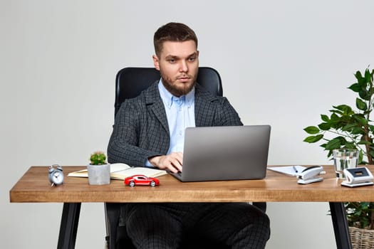 young man sitting on chair at table and resting, using laptop