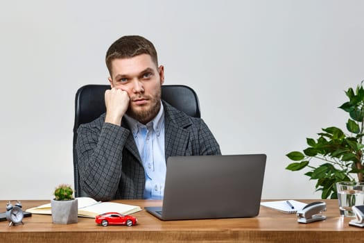 young man sitting on chair at table and resting, using laptop