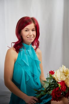 Beautiful woman with red hair in yellow dress on light background holds a large bouquet of roses flowers. Inernational woman's day 8 March