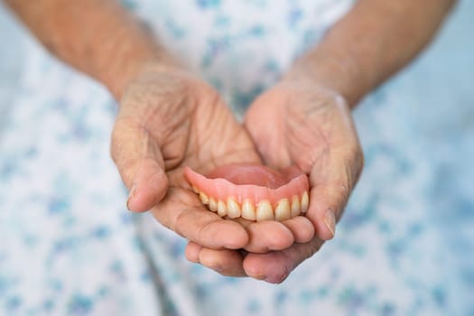 Asian elderly woman patient holding to use denture, healthy strong medical concept.