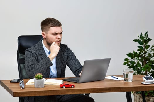 young man thinking about online project while looking at laptop pc computer at workplace