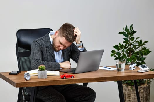 Exhausted tired man using laptop pc computer, sitting on chair at desk, having problems thinking about troubles