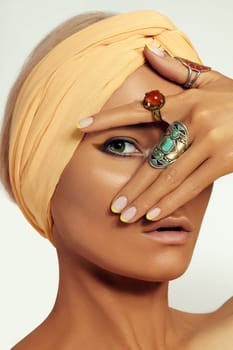 Beauty young Woman wearing Turban. Oriental Boho Style with Bohemian Accessories, Beautiful Rings, Fashion Make-up. Tanned Smooth Skin, Dark Arabian Makeup, Luxury Jewelry Rings and Perfect Manicure
