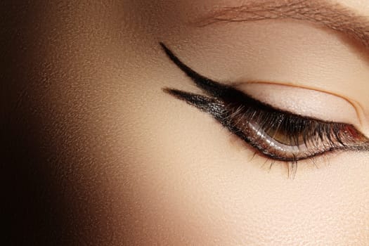 Beautiful macro shot of female eye with classic eyeliner makeup. Perfect shape of eyebrows, brown eyeshadows and long eyelashes. Cosmetics and make-up. Closeup macro shot of fashion liner eyes visage