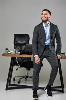 bearded male photographer smiling cheerfully while working at her desk.