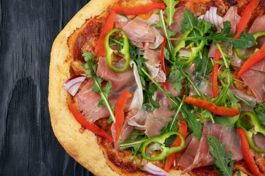 Italian Pizza on plate with jamon slices, pepper and fresh arugula leaves on top