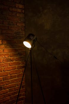 Vintage rustic lamp fixed on tripod on a brick wall background