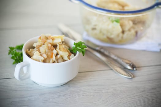 cooked dumplings with potatoes and fried onions, in a bowl on a wooden table.