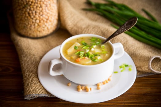 dried pea soup in a plate with herbs, on a wooden table.