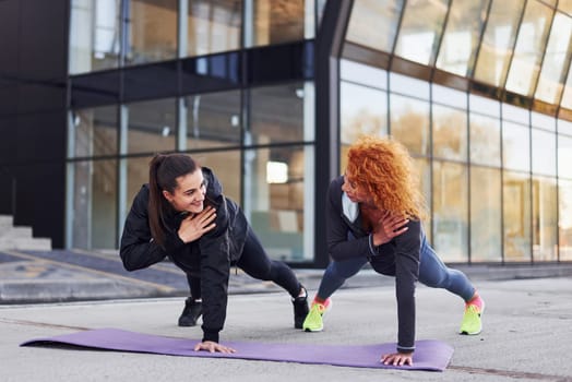 Doing push ups. Two female friends with sportive bodies have fitness day outdoors.