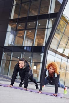 Doing push ups. Two female friends with sportive bodies have fitness day outdoors.