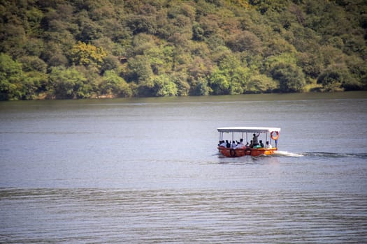 aerial drone shot of handmade boat used by rural villagers to cross over lakes like Dhebar, Pichola from tree covered mountains as a ferry service