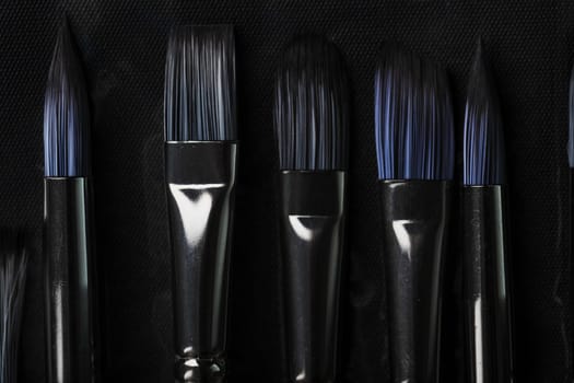 A set of oil brushes and palette knife isolated on a black background, Close-up