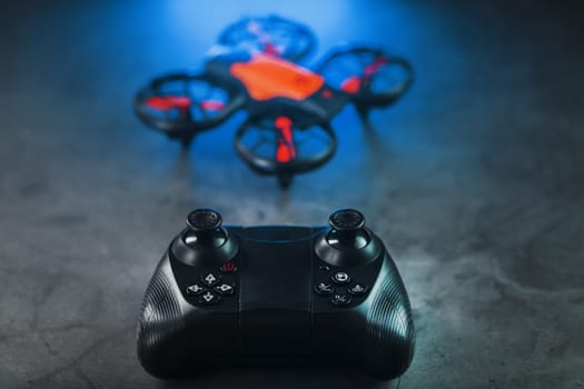 Quadcopter drone with joystick control and blue neon backlight, on a dark textured background