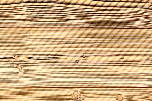 Top view - desk made from wooden boards lit by morning sun, shades leaving diagonal stripes pattern. Abstract wooden background.
