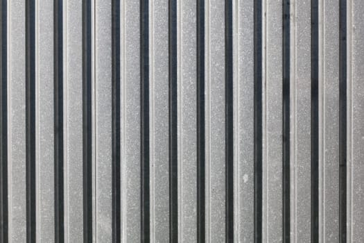 Metal plate fence, sun shining from side. Abstract construction background.
