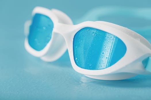 White swimming goggles on a blue background in a minimalist style with free space