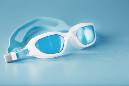 Swimming goggles in a white frame with a blue filter on a blue background