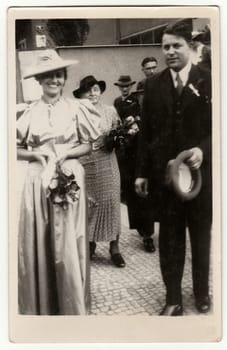 PRAHA (PRAGUE), THE CZECHOSLOVAK REPUBLIC - JUNE 27, 1939: Vintage photo shows newlyweds go from wedding ceremony. Retro black and white studio photography. Circa 1940s.