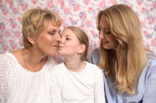 A teenage girl hugs and kisses her grandmother and mother, expresses her love to them.