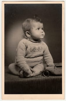 OLOMOUC, THE CZECHOSLOVAK REPUBLIC - CIRCA 1940s: Vintage photo shows a small boy - toddler with toy car. Retro black and white photography. Circa 1940s.