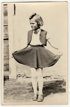 THE CZECHOSLOVAK REPUBLIC - CIRCA 1940s: Vintage photo shows a young girl outdoors. She shows her skirt proudly. Retro black and white photography. Circa 1940s.