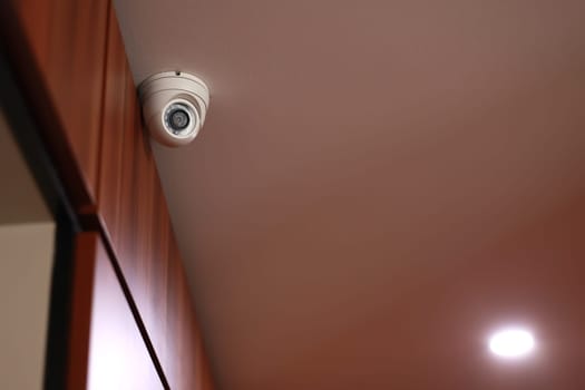 Indoor CCTV monitoring, white round security camera or surveillance system in office building, hotel hall, shopping center on ceiling. Concept of surveillance and monitoring all day and night.
