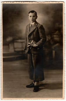 ZEDELGEM, BELGIUM - CIRCA 1920s: Vintage photo shows boy poses in a photography studio. Retro black and white photography. Circa 1910s.