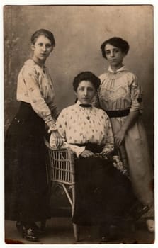 ZEDELGEM, BELGIUM - CIRCA 1920s: Vintage photo shows girls with Edwardian hairstyle pose in a photography studio. Retro black and white photography. Circa 1920s.