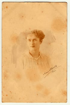 GERMANY - APRIL, 1917: Vintage photo shows a young girl. She wears Edwardian hairstyle. Retro black and white photography with sepia effect. Circa 1920s.