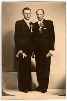 ZLIN, THE CZECHOSLOVAK REPUBLIC - CIRCA 1920s: Vintage photo shows two men - groom and his best man pose in photography studio. Retro black and white photography. Circa 1920s.