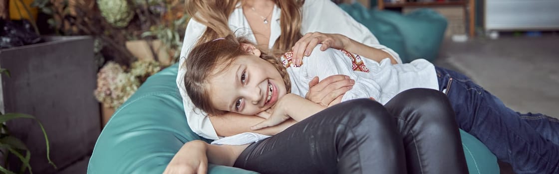 Happy caucasian mother with young beautiful cheerful daughter are having time together