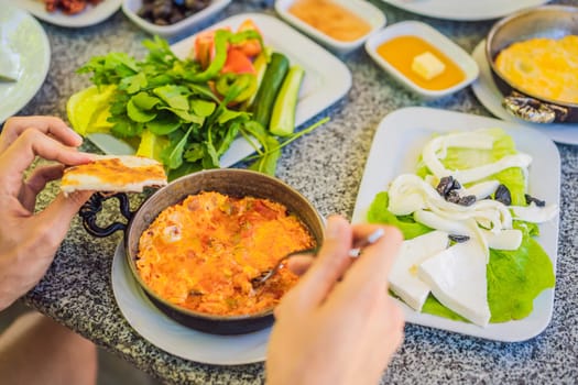 Turkish breakfast table. Pastries. Vegetables. Olives. Cheeses, fried eggs. Jams, tea in copper pot and tulip glasses. Wide composition.