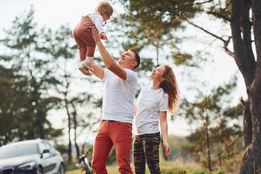 Father and mother spending weekend outdoors near forest with daughter.