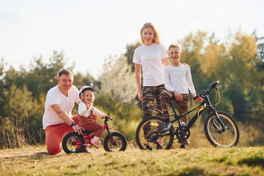 With bikes. Happy family spending weekend together outdoors near the forest. With daughter and son.