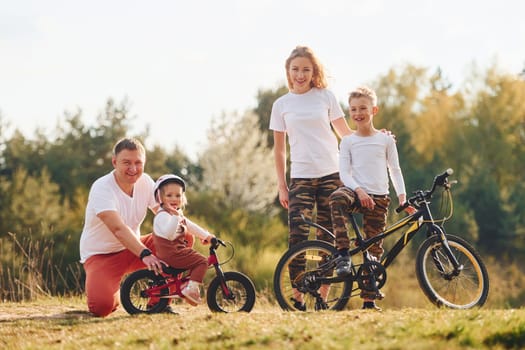 With bikes. Happy family spending weekend together outdoors near the forest. With daughter and son.