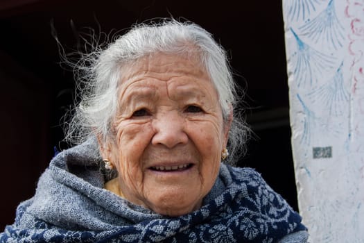 close-up of old lady with white hair and many wrinkles on her face looks at camera. look at camera with puzzled face
