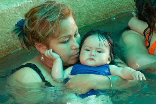 mother in the water with her baby daughter teaching to swim. hot springs and pool