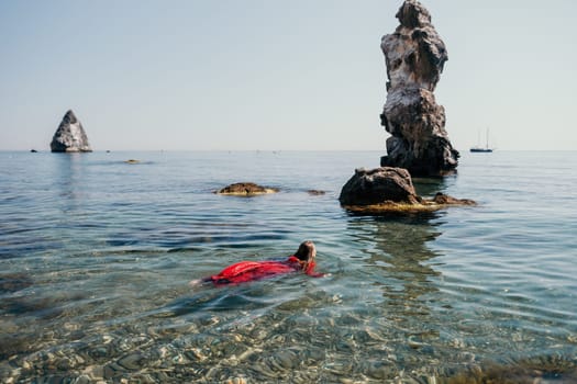 Woman travel sea. Happy tourist taking picture outdoors for memories. Woman traveler looks at the edge of the cliff on the sea bay of mountains, sharing travel adventure journey.