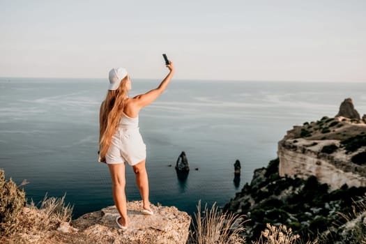 Woman travel sea. Young Happy woman in a long red dress posing on a beach near the sea on background of volcanic rocks, like in Iceland, sharing travel adventure journey