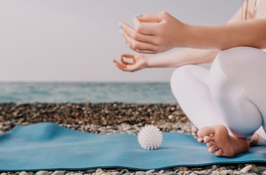 Woman yoga sea. Young woman with braids dreadlocks in white swimsuit and boho style braclets practicing outdoors on yoga mat by the ocean on sunny day. Women's yoga fitness routine. Healthy lifestyle, harmony