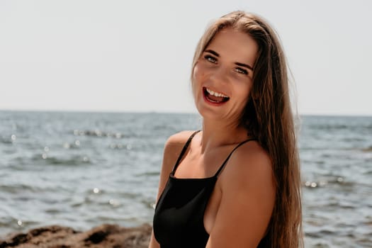 Woman travel sea. Young Happy woman in a long red dress posing on a beach near the sea on background of volcanic rocks, like in Iceland, sharing travel adventure journey