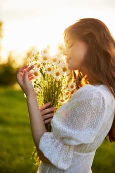 close-up portrait of a woman in a light dress in a field during sunset with a bouquet of daisies in her hands in backlight. High quality photo