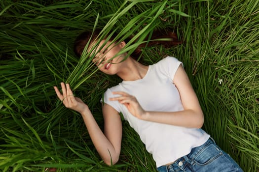 happy woman lies in tall grass covering her face with leaves. High quality photo