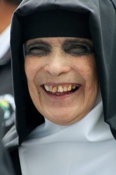 closeup of a smiling Nun with broken tooth and bruises on her eyes. High quality photo. wears the wet habit