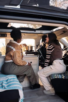 two young friends in a road trip cooking in camper van, concept of freedom and travel adventure